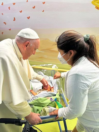 FILE-- In this image made available by Vatican Media, Pope Francis caresses an infant before baptizing him with the name of Miguel Angel, Friday, March 31, 2023, inside the Agostino Gemelli University Polyclinic where he was treated for bronchitis. The family of the infant sent a get-well-soon note to Francis, Thursday, June 8, 2023, after he underwent surgery on Wednesday to repair a hernia in his abdominal wall. (AP Photo/Vatican Media, file)