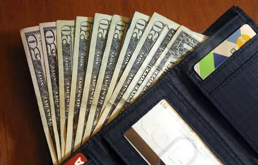 In this June 15, 2018, file photo, cash is fanned out from a wallet in North Andover, Mass.  Retirement planning is part savings, part guessing game. How much will you need? While many of your day-to-day expenses will remain the same, some big-ticket items can take a large bite out of your savings. (AP Photo/Elise Amendola, File)