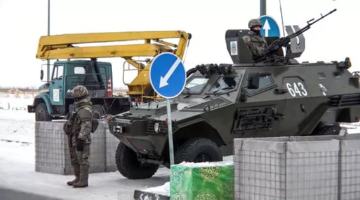 In this image taken from footage provided by the RU-RTR Russian television, A Kazakhstan's soldier stands next to a military vehicle at a check point in Kazakhstan, Friday, Jan. 7, 2022. Over 70 cargo planes are being deployed in Russia's peacekeeping mission in Kazakhstan according to the Defense Ministry chief spokesman's briefing on Friday, after the worst street protests since the country gained independence three decades ago. The demonstrations began over a near-doubling of prices for a typ