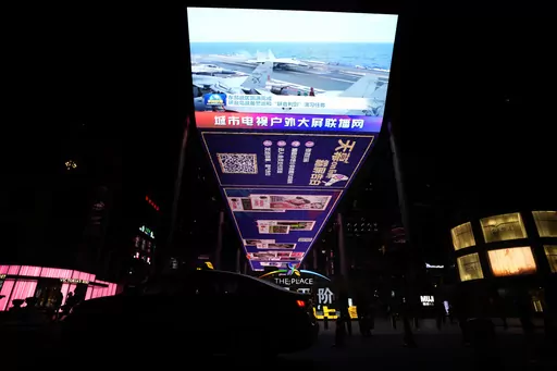 The evening news broadcast shows Chinese fighter jets on an aircraft carrier with the Chinese subtitles "Eastern Battle District successfully concludes the patrol exercise around the taiwan island and Joint Sword exercise" on an outdoor screen in Beijing, Monday, April 10, 2023. China's military declared Monday it is "ready to fight" after completing three days of large-scale combat exercises around Taiwan that simulated sealing off the island in response to the Taiwanese president's trip to the