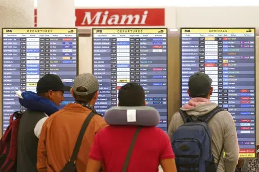 Travelers check their flights at Miami International Airport, Saturday, July 2, 2022, in Miami. The Fourth of July holiday weekend is jamming U.S. airports with the biggest crowds since the pandemic began in 2020. (AP Photo/Marta Lavandier)