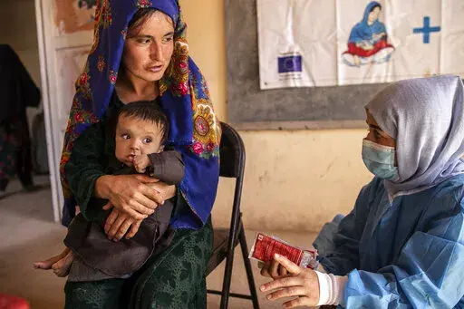 A Save the Children nutrition counsellor, right, explains to Nelab, 22, how to feed her 11-month-old daughter, Parsto, with therapeutic food, which is used to treat severe acute malnutrition, in Sar-e-Pul province of Afghanistan, Thursday, Sept. 29, 2022. A senior U.N. official in Afghanistan met the deputy prime minister of the Taliban-led government to discuss a ban on women working for non-governmental groups. Save the Children is one of the major aid agencies that suspended its operations in