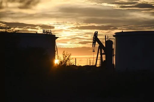 The sun begins to set behind crude oil tanks and a pumpjack, July 5, 2022, in Midland, Texas. The IEA’s annual world energy outlook, which analyzes the global picture of energy supply and demand, was released Tuesday, Oct. 24, 2023. (Eli Hartman/Odessa American via AP, File)