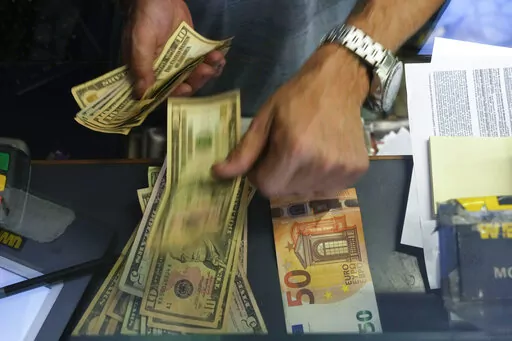 A cashier changes a 50 Euro banknote with US dollars at an exchange counter in Rome, Wednesday, July 13, 2022. The euro on Tuesday fell to parity with the dollar for the first time in nearly 20 years. (AP Photo/Gregorio Borgia)