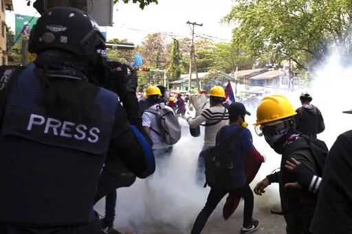 A photographer wearing a protective vest with a 'press' sign at the back films an anti-military government protest being dispersed with tear gas by security forces in Sanchaung township in Yangon, Myanmar on March 3, 2021. Since Myanmar's military dismissed the results of democratic elections and seized power on Feb. 1, 2021, peaceful nationwide protests and violent crackdowns by security forces have spiraled into a nationwide humanitarian crisis. (AP Photo)