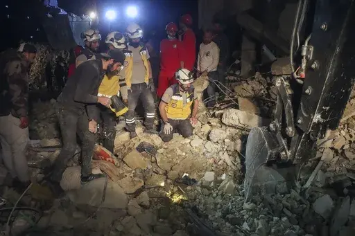 In this photo provided by the Syrian Civil Defense White Helmets, members of their team search through the debris of a four-story building after an ordnance from Syria's 13-conflict exploded in the coastal city of Latakia, Syria, early Sunday, March 16, 2025. 2025. The White Helmets said it worked overnight and recovered 16 bodies. (Syrian Civil Defense White Helmets via AP)