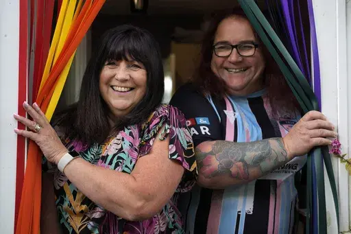 Avril Clark, left, and Lucy pose for a photograph during an interview at their house in London, Tuesday, June 11, 2024. Avril Clark operates the group Distinction Support, a U.K.-based global online network that helps people whose partner went through or is undergoing a gender transition. Her spouse, a British soccer referee at the time, came out publicly as transgender in 2018, changed her name to Lucy and brought the couple much attention. Avril Clark says that until then, they kept their arra