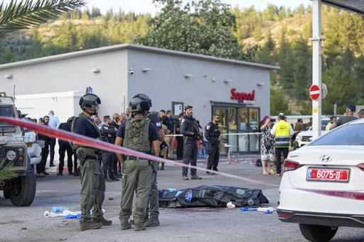 Israeli police stand next to the body of a Palestinian gunman at the scene of a shooting attack near the West Bank Israeli settlement of Eli, Tuesday, June 20, 2023. Israeli medics say that an attacker has opened fire at a gas station near an Israeli settlement in the West Bank, killing at least four people and wounding several more (AP Photo/Ohad Zwigenberg)
