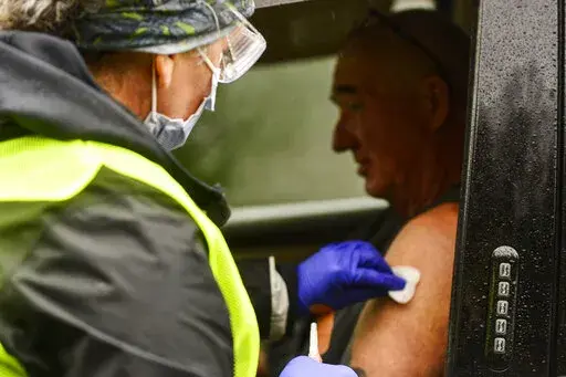 FILE - Registered nurse Megan Chamberlain gives a flu shot to Anthony Devitt, of Marlboro, Vt., during a flu vaccine clinic on Route 9, in Brattleboro, Vt., that was hosted by Visiting Nurse and Hospice for Vermont and New Hampshire on Tuesday, Oct. 26, 2021. (Kristopher Radder/The Brattleboro Reformer via AP, File)