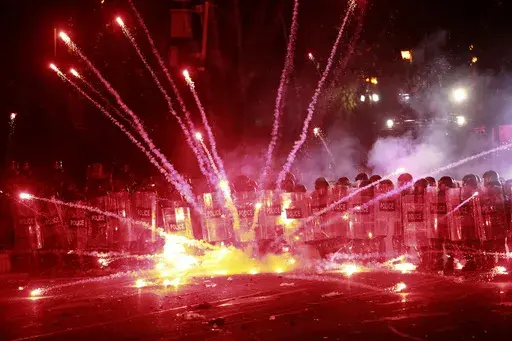 Demonstrators use firecrackers against police during a rally against the government's decision to suspend negotiations on joining the European Union for four years, outside the parliament's building in Tbilisi, Georgia, early Sunday, Dec. 1, 2024. (AP Photo/Zurab Tsertsvadze)