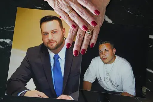 Cheryl Juaire holds photos of her sons, both of whom died from overdoses, Sean Merrill, left, and Corey Merrill, after making a statement during a hearing in New York, Thursday, March 10, 2022. Victims of opioids and those who have lost loved ones to the addiction crisis are unleashing their emotions on members of the family they blame for fueling the deadly epidemic. Thursday's unusual hearing is being conducted virtually in U.S. Bankruptcy Court in New York. It is giving people the chance to c