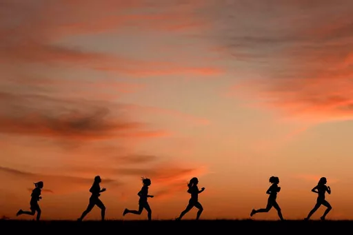 High school students run at sunset as they practice for the track and field season Monday, Feb. 28, 2022, in Shawnee, Kan. New research hints that even simple exercise just might help fend off memory problems. While physical activity helps keep healthy brains fit, it's not clear how much it helps once memory starts to slide.  (AP Photo/Charlie Riedel, File)