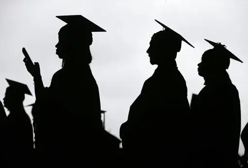 In this May 17, 2018, file photo, new graduates line up before the start of the Bergen Community College commencement at MetLife Stadium in East Rutherford, N.J.  A deadline is fast approaching for teachers, librarians, nurses and others who work in public service to apply to have their student loan debt forgiven. New figures from the U.S. Department of Education show 145,000 borrowers have had the remainder of their debt canceled through the Public Service Loan Forgiveness program. (AP Photo/Se