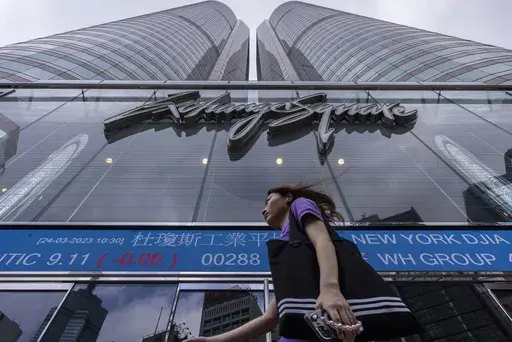 A pedestrian passes by the Hong Kong Stock Exchange electronic screen in Hong Kong, Friday, March 24, 2023. Shares fell Friday in Asia as worries over turmoil in the banking sector and recession risks overshadowed gains on Wall Street.(AP Photo/Louise Delmotte)