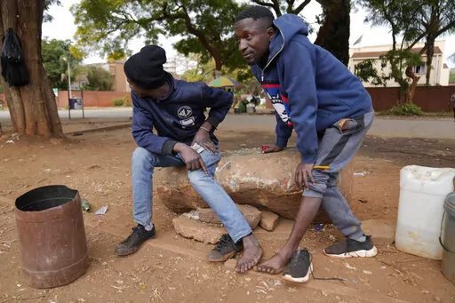 Street vendors take off their shoes to show their toes on the streets of Harare, Zimbabwe, Thursday, June, 9, 2022. Rampant inflation is making it increasingly difficult for people in Zimbabwe to make ends meet. Since the start of Russia’s war in Ukraine, official statistics show that Zimbabwe’s inflation rate has shot up from 66% to more than 130%. The country's finance minister says the impact of the Ukraine war is heaping problems on the already fragile economy. (AP Photo/Tsvangirayi Mukw