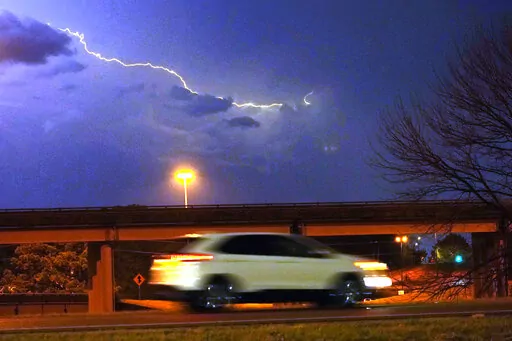 A vehicle races along a Jackson, Miss., street as lightning streaks across the sky, Tuesday evening, Nov. 29, 2022. Area residents were provided a light show as severe weather accompanied by some potential twisters affected parts of Louisiana and Mississippi. (AP Photo/Rogelio V. Solis)
