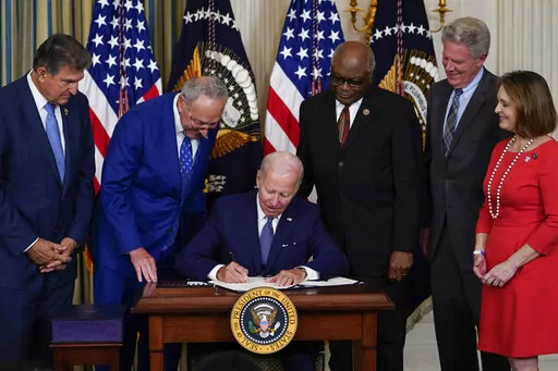 President Joe Biden signs the Democrats' landmark climate change and health care bill in the State Dining Room of the White House in Washington, Tuesday, Aug. 16, 2022, as from left, Sen. Joe Manchin, D-W.Va., Senate Majority Leader Chuck Schumer of N.Y., House Majority Whip Rep. James Clyburn, D-S.C., Rep. Frank Pallone, D-N.J., and Rep. Kathy Castor, D-Fla., watch. (AP Photo/Susan Walsh)