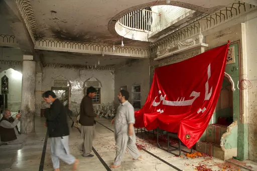 People visit Kusha Kisaldar Shiite Mosque, the site of March 4 suicide bombing, to offer prays for bombing victims, in Peshawar, Pakistan, Wednesday, March 9, 2022. In northwest Pakistan the remains of an IS suicide bomber are still visible on the once ornate walls of a mosque where last month more than 63 worshippers died as they knelt in prayer. The bomber, an Afghan identified by IS as Julaybib al-Kabuli, was from the capital Kabul. (AP Photo/Muhammad Sajjad)