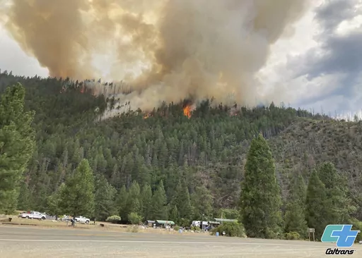 In this photo provided by Caltrans, smoke rises from the Head Fire in Klamath National Forest, Calif., on Tuesday Aug. 15, 2023. A wildfire pushed by gusty winds from a thunderstorm raced through national forest land near California's border with Oregon, prompting evacuations in the rural area. The blaze in Siskiyou County was one of at least 19 fires that erupted in the Klamath National Forest as thunderstorms rolling through the area brought lightning and downdrafts that drove the flames throu