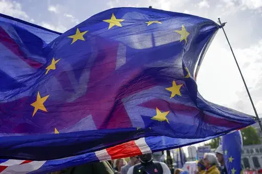 A Union flag waves behind a European Union flag, outside the Houses of Parliament, in London, Wednesday, Oct. 19, 2022. The British government on Sunday, Nov. 20, 2022 denied a report it is seeking a “Swiss-style” relationship with the European Union that would remove many of the economic barriers erected by Brexit — even as it tries to repair ties with the bloc after years of acrimony. (AP Photo/Alberto Pezzali, File)