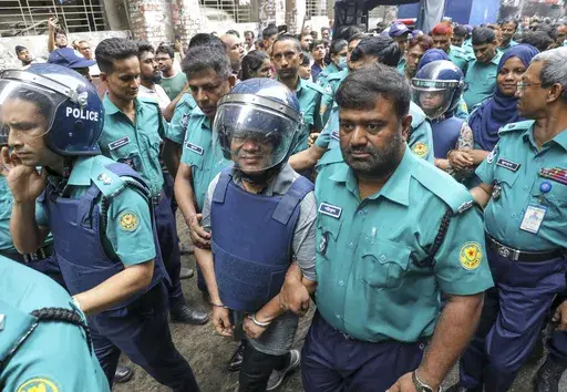Police officers escort Shakil Ahmed, Ekattor television's former head of news, center, and its former chief correspondent Farzana Rupa, rear right in helmet, to the court of the Chief Metropolitan Magistrate in Dhaka, Bangladesh, Thursday, Aug. 22, 2024. (AP Photo)
