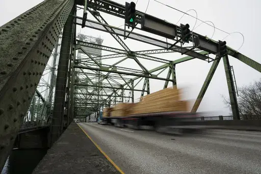 A logging truck drives on the Interstate 5 bridge that spans the Columbia River and connects Portland, Ore., with southwest Washington state, Feb. 13, 2024. Dozens of aging bridges, including this Interstate 5 bridge, in 16 states will be replaced or improved with the aid $5 billion of federal grants announced Wednesday, July 17, by President Joe Biden's administration as the latest beneficiaries of a massive infrastructure law. (AP Photo/Jenny Kane, File)