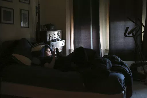 James Walter uses a phone at home in the Queens borough of New York, on April 7, 2021. Sleep scientists long ago established that insufficient sleep is linked with poor health outcomes, anxiety, obesity and several other negative effects. The research is equally conclusive that smartphones are particularly disruptive to the circadian clock that regulates sleep and other hormones. (AP Photo/Jessie Wardarski, File)