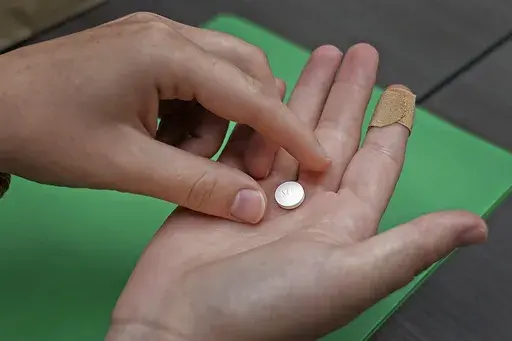 A patient prepares to take the first of two combination pills, mifepristone, for a medication abortion during a visit to a clinic in Kansas City, Kan., Oct. 12, 2022. (AP Photo/Charlie Riedel, File)