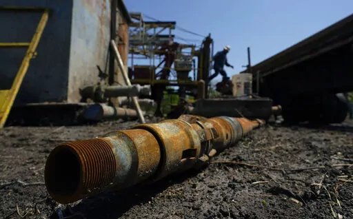 An oil well worker moves equipment at a site on the Rooke family ranch where an orphaned well was plugged, Tuesday, May 18, 2021, near Refugio, Texas. The Interior Department is giving 24 states a total of $560 million to start cleaning high-priority derelict oil and gas wells abandoned on state and private land, the department said Thursday, Aug. 25, 2022. (AP Photo/Eric Gay, File)