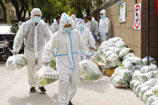 In this photo released by Xinhua News Agency, volunteers carry daily necessities for residents in Fengxian District in eastern China's Shanghai city on Monday, March 28, 2022. China began its most extensive coronavirus lockdown in two years Monday to conduct mass testing and control a growing outbreak in Shanghai as questions are raised about the economic toll of the nation's "zero-COVID" strategy. (Wang Yanting/Xinhua via AP)