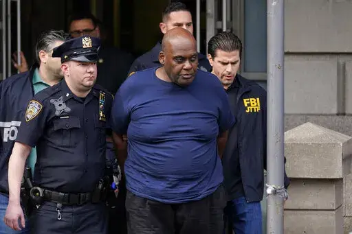 New York City Police and law enforcement officials lead subway shooting suspect Frank James, center, away from a police station, in New York, Wednesday, April 13, 2022. On Friday, May 6, 2022, a federal grand jury indicted James in the attack that wounded multiple people and rattled a city already experiencing a rise in violent crime. (AP Photo/Seth Wenig, File)