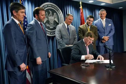 Republican Gov. Tate Reeves, seated, signs a bill that will reduce the state income tax over four years, beginning in 2023, at his office in Jackson, Miss., Tuesday, April 5, 2022. Attending the signing were from left, Senate Appropriations Committee Chairman Briggs Hopson, R-Vicksburg, Senate Finance Committee Chairman Josh Harkins, R-Flowood, House Speaker Pro Tempore Jason White, R-West, House Ways and Means Committee Chairman Trey Lamar, R-Senatobia and House Speaker Philip Gunn, R-Clinton. 