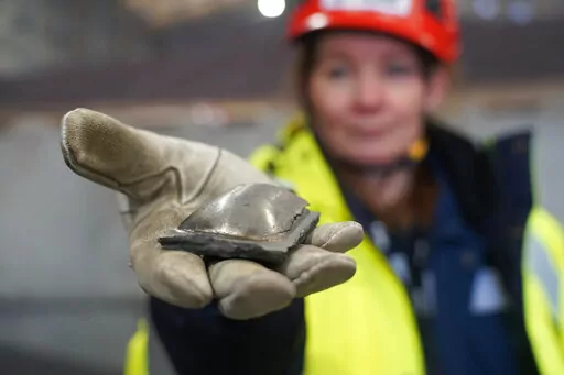 Susanne Rostmark, research leader, LKAB, holds a piece of hot briquetted iron ore made using the HYBRIT process nearby the venture’s pilot plant in Lulea, Sweden on Feb. 17,  2022. The steel-making industry is coming under increasing pressure to curb its environmental impact and contribute to the Paris climate accord, which aims to cap global warming at 1.5 degrees Celsius  (James Brooks via AP)