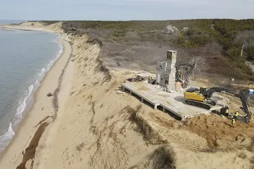 The remains of a home sit atop of a sandy bluff overlooking a beach in Wellfleet, Mass., Tuesday, Feb. 25, 2025. (AP Photo/Andre Muggiati)