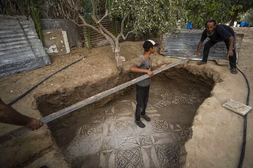 Palestinians clean around a Byzantine-era mosaic floor that was uncovered recently by a farmer in Bureij in central Gaza Strip, Sept. 5, 2022. The man says he stumbled upon it while planting an olive tree last spring and quietly excavated it over several months with his son. Experts say the discovery of the mosaic — which includes 17 well-preserved images of animals and birds — is one of Gaza's greatest archaeological treasures. They say it's drawing attention to the need to protect Gaza's a