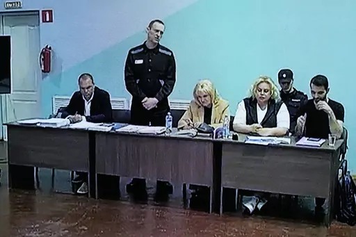 A view of a TV Screen showing Russian opposition leader Alexei Navalny, 2nd left, between his lawyers in a courtroom, via video link provided by the Russian Federal Penitentiary Service, during a preliminary hearing, in Melekhovo, Vladimir region, about 260 kilometers (163 miles) northeast of Moscow, Russia, on Monday, June 19, 2023. A Russian court has opened a new trial of imprisoned Russian opposition leader Alexei Navalny that could keep him behind bars for decades. (AP Photo/Alexander Zemli