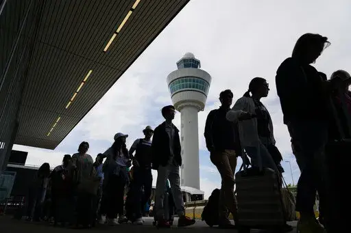 Travelers wait in long lines outside the terminal building to check in and board flights at Amsterdam's Schiphol Airport, Netherlands, Tuesday, June 21, 2022. After two years of pandemic restrictions, travel demand is back with a vengeance but airlines and airports that slashed jobs during the depths of the COVID-19 crisis are struggling to keep up. With the busy summer tourism season underway in Europe, passengers are encountering chaotic scenes at airports, including lengthy delays, canceled f