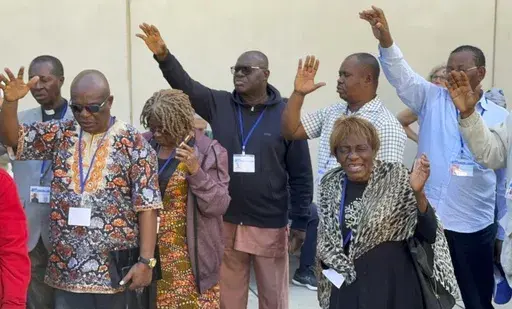 African delegates to the General Conference of the United Methodist Church pray outside the Charlotte Convention Center, in Charlotte, N.C., Thursday, May 2, 2024. (AP Photo/Peter Smith, File)