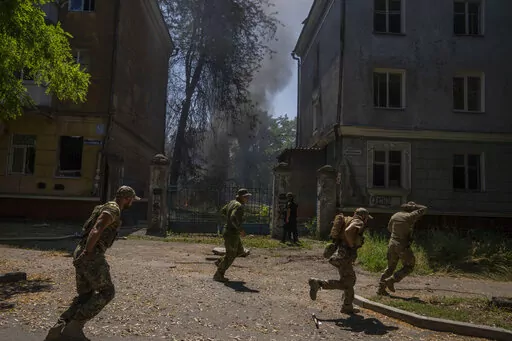 Ukrainian soldiers run after a missile strike hit a residential area, in Kramatorsk, Donetsk region, eastern Ukraine, Thursday, July 7, 2022. Injured residents sat dazed and covered in blood. A crater was now the centre of the courtyard. Last week, the governor of the Donetsk oblast Pavlo Kyrylenko urged the province's more than 350,000 remaining residents to flee to safer towns further West, saying that evacuating the region was necessary to save lives and allow the Ukrainian army to better def