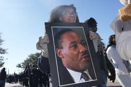 Garland High School senior Saron Lias carries a poster of Dr. Martin Luther King Jr. while marching in the 36th annual MLK Day Parade in Garland, Texas, Saturday, Jan. 18, 2025. (AP Photo/LM Otero)