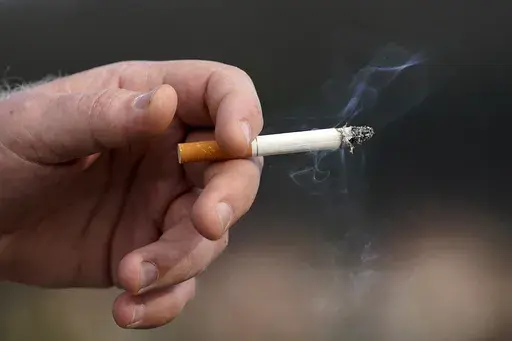 A man holds a lit cigarette while smoking in San Francisco, Wednesday, Dec. 2, 2020. (AP Photo/Jeff Chiu, File)