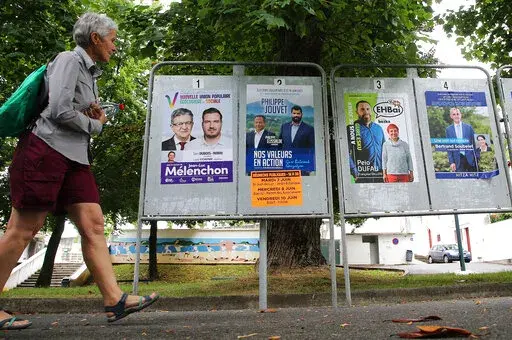 A woman walks past electoral posters of the upcoming parliamentary elections in Saint Jean de Luz, southwestern France, Wednesday June 8, 2022. The legislative elections will take place on June 12 and 19, 2022. (AP Photo/Bob Edme)