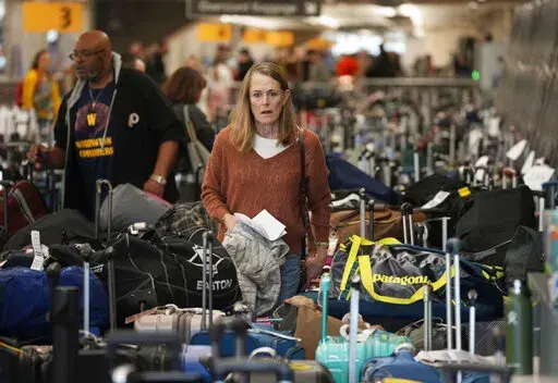 A traveler wades through a field of unclaimed bags at the Southwest Airlines luggage carousels at Denver International Airport, Dec. 27, 2022, in Denver. With its flights now running on a roughly normal schedule, Southwest Airlines is turning its attention to luring back customers and repairing damage to a reputation for service after canceling 15,000 flights around Christmas. The disruptions started with a winter storm and snowballed when Southwest's ancient crew-scheduling technology failed.(A