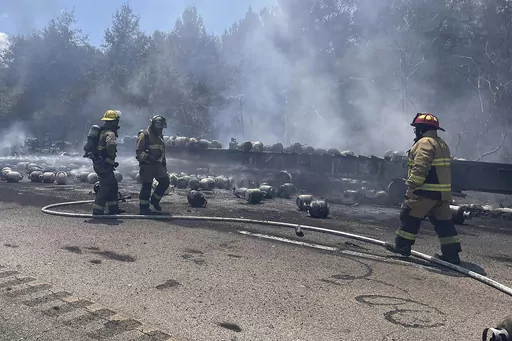 In this photo released by the Mississippi Highway Patrol, firefighters work to stop a fire from spreading from a semitrailer, which was carrying propane tanks, on Interstate 59 near Poplarville, Miss., on Monday, Aug. 14, 2023. The interstate was closed after the truck caught fire. (Mississippi Highway Patrol via the Mississippi Department of Public Safety via AP)