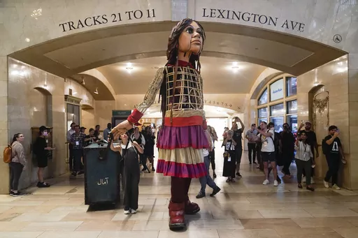 A 12-foot puppet of a 10-year-old Syrian refuge named Little Amal walks around Grand Central Station in New York, on Sept. 15, 2022. Little Amal will journey across the United States this fall, visiting key places in America’s history in an attempt to raise awareness about immigration and migration.(AP Photo/Seth Wenig, File)