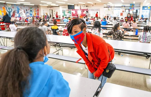 Joy Faulkner, of Robinson Twp., Pa., meets first graders at Langley K-8 School on Thursday, Dec. 23, 2021, in Sheraden neighborhood in Pittsburgh. Faulkner's son, former Pitt and now Buffalo Bills player Dane Jackson, provided lunch and backpacks to students at the school. (Andrew Rush/Pittsburgh Post-Gazette via AP)