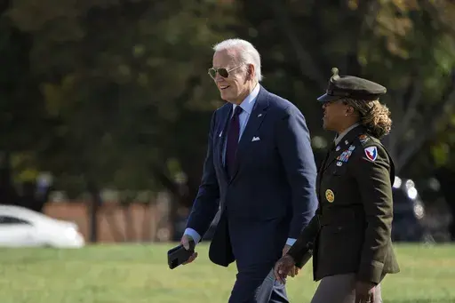 President Joe Biden, left, is escorted by Col. Tasha N. Lowery as he walks from Marine One after arriving at Fort McNair in Washington, Monday, Oct. 28, 2024. (AP Photo/Ben Curtis)