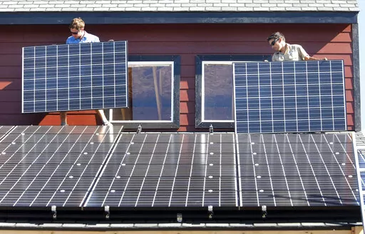 Workers install two of 105 solar panels on the roof of a barn Thursday, Aug. 27, 2009, north of Hesperus, Colo. The Inflation Reduction Act includes tax credits and rebates for homeowners who make energy-saving updates to their homes. Tax credits are available now for updates like new windows, doors, air conditioners, insulation and solar panels, while larger rebates for energy-saving and electrification updates are expected to become available later this year or early next year. (AP Photo/Jerry