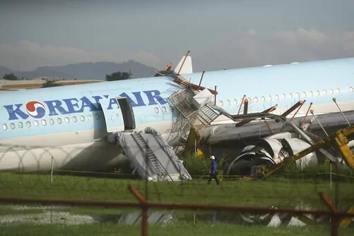 A man walks beside a damaged Korean Air plane after it overshot the runway at the Mactan-Cebu International Airport in Cebu, central Philippines early Monday Oct. 24, 2022. The Korean Air plane overshot the runway while landing in bad weather in the central Philippines late Sunday, but authorities said all 173 people on board were safe. (AP Photo/Juan Carlo De Vela)