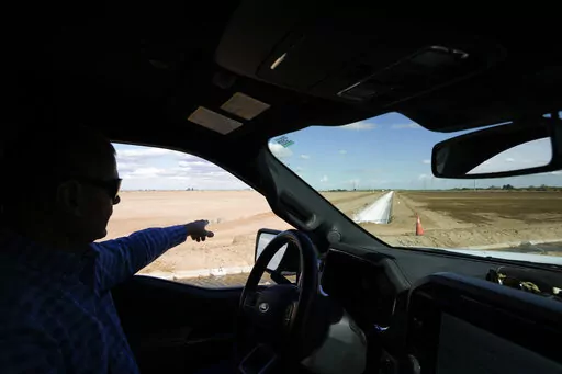 Tom Brundy points to a newly built irrigation canal on one of the fields at his farm Tuesday, Feb. 28, 2023, near Calexico, Calif. Brundy, an alfalfa grower in California's Imperial Valley, thinks farmers reliant on the shrinking Colorado River can do more to save water and use it more efficiently. But one practice that's off-limits for Brundy is fallowing — leaving fields unplanted to spare the water that would otherwise irrigate crops. (AP Photo/Gregory Bull)